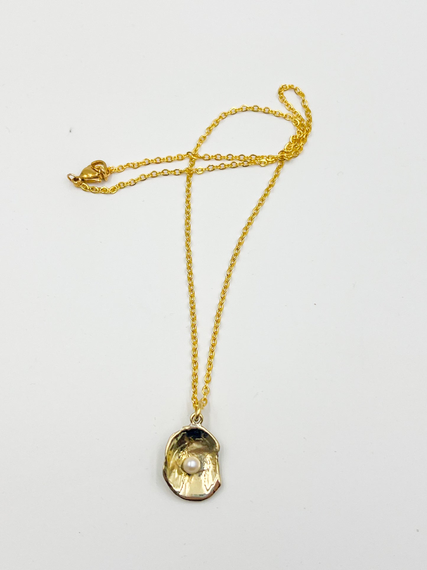 Gold necklace with a shell pendant on a white background