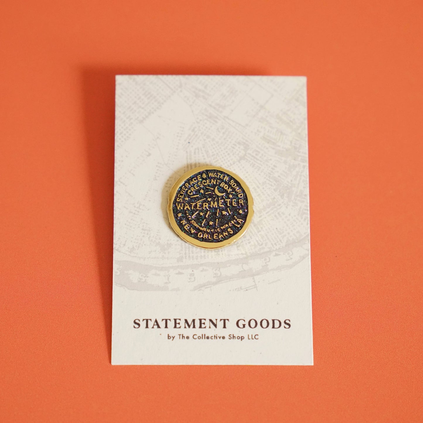 Add a touch of New Orleans to your style with the New Orleans Water Meter Enamel Pin by Statement Goods. This local artist-made pin features a gold and black glittery enamel, measuring 1"x1" and secured with a black rubber backing. Show off your quirky side with this unique accessory!