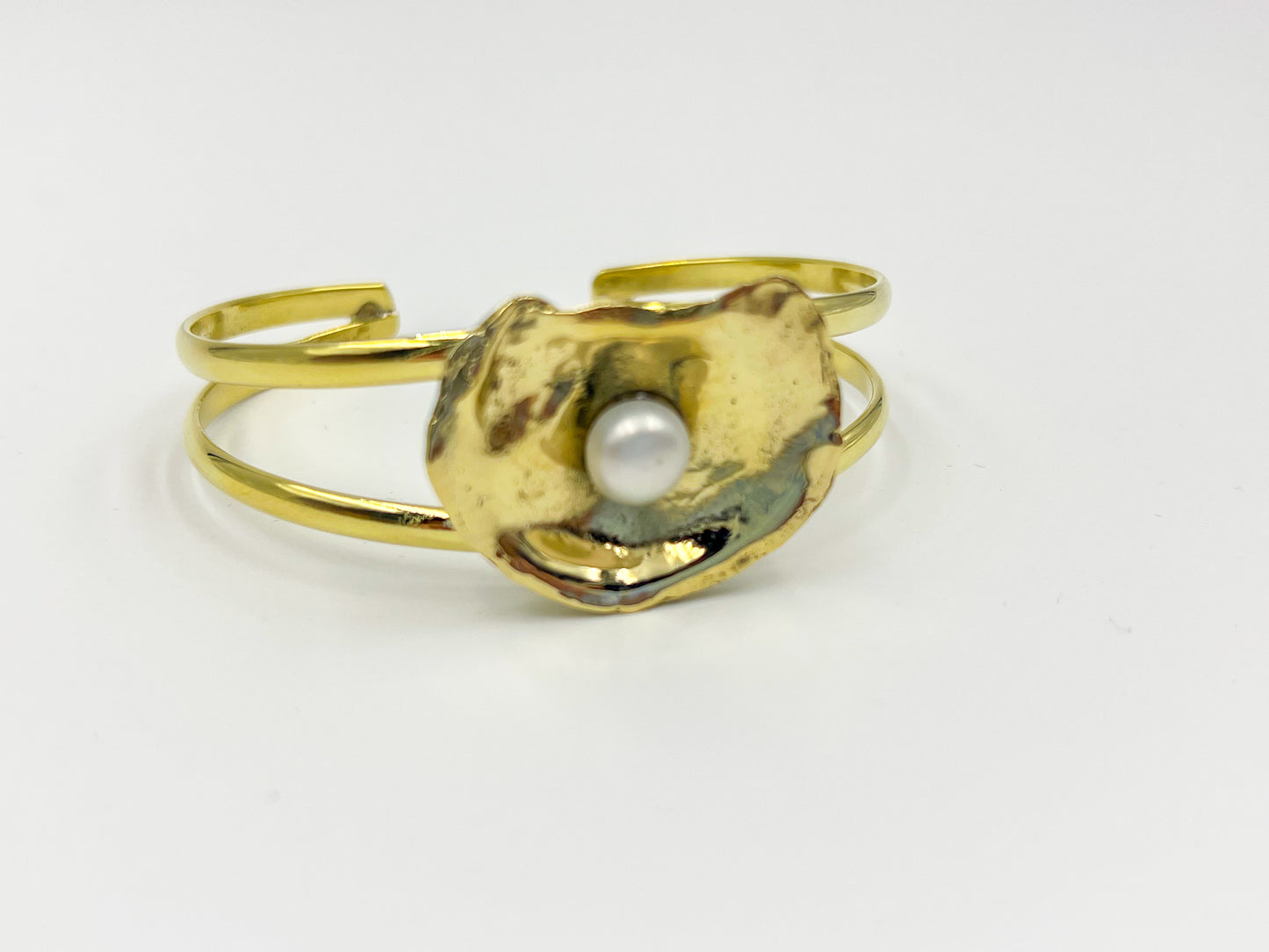 Gold bracelet with a central pearl on a white background