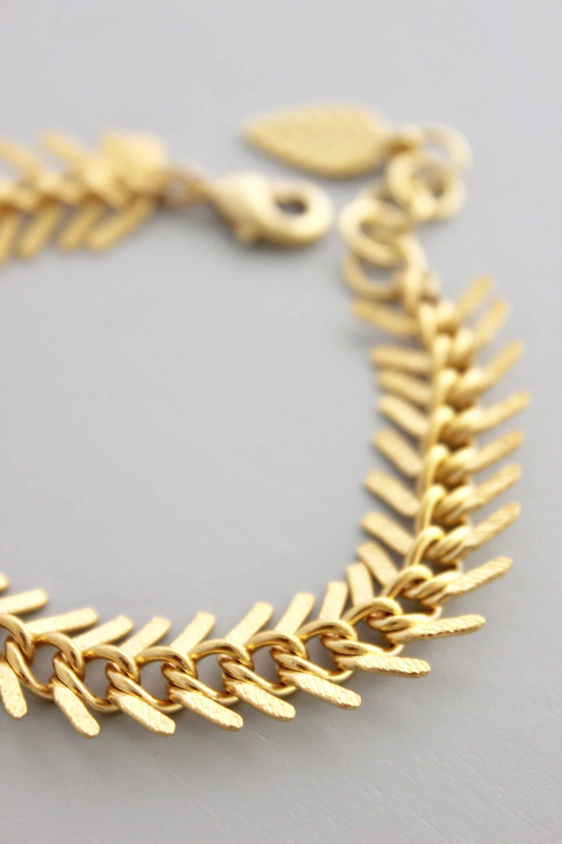 Gold bracelet with leaf-like links on a light gray background
