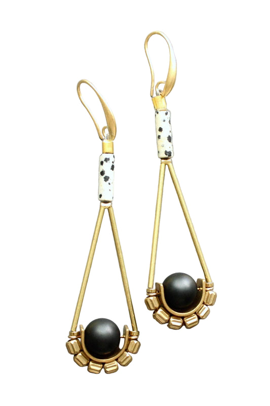 Gold earrings with black beads on a light gray background
