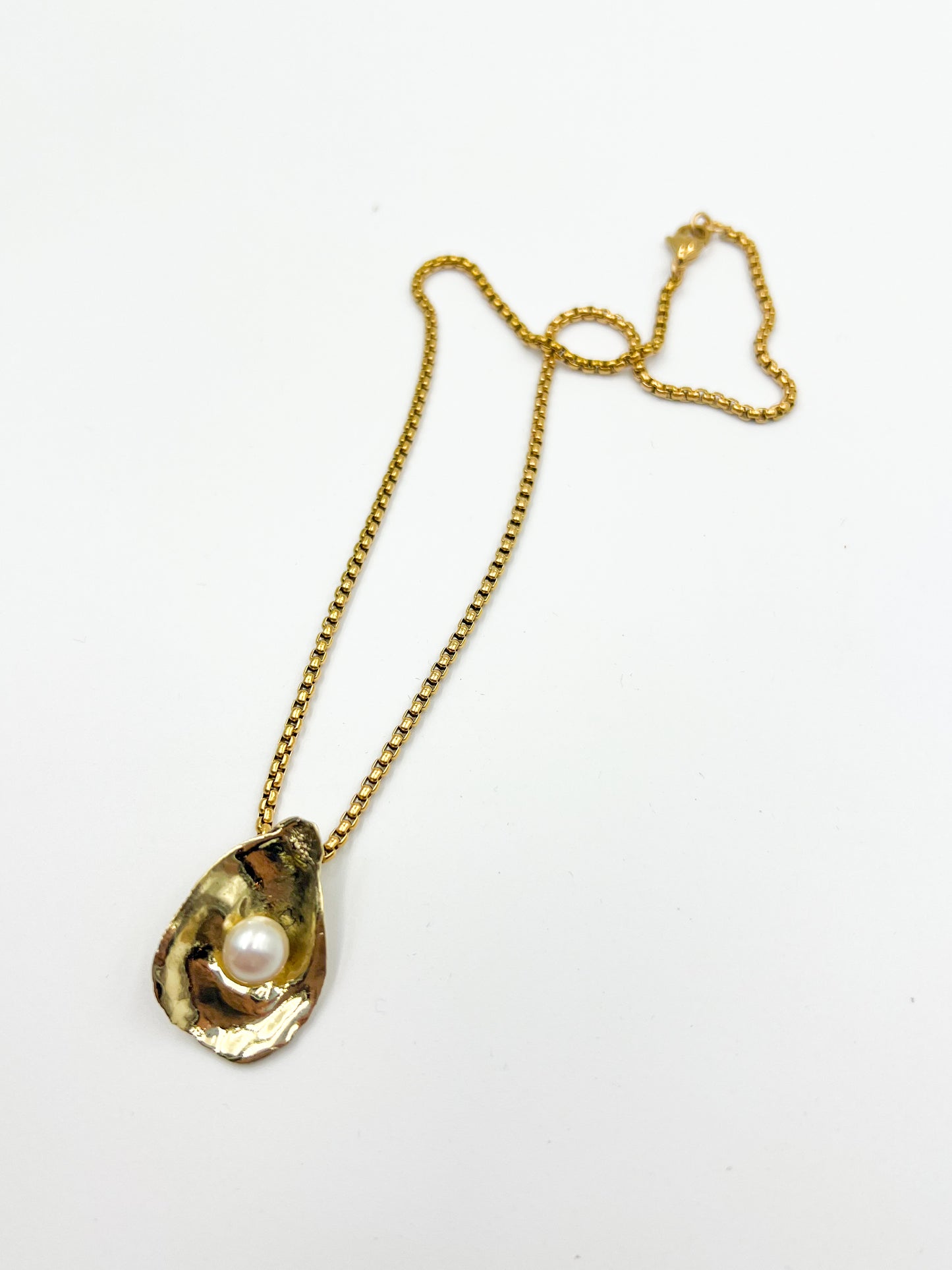 Gold necklace with a pendant featuring a pearl on a white background