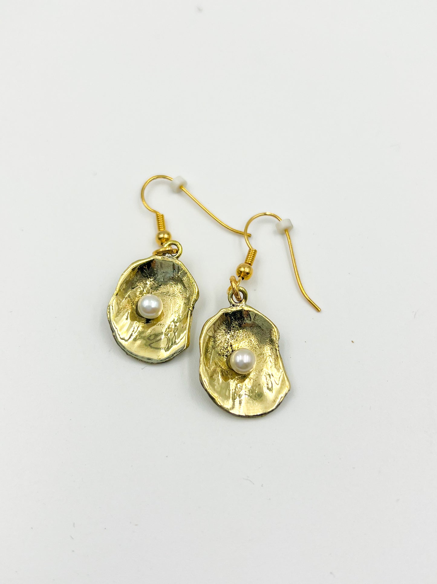 Gold earrings with pearl centers on a light gray background