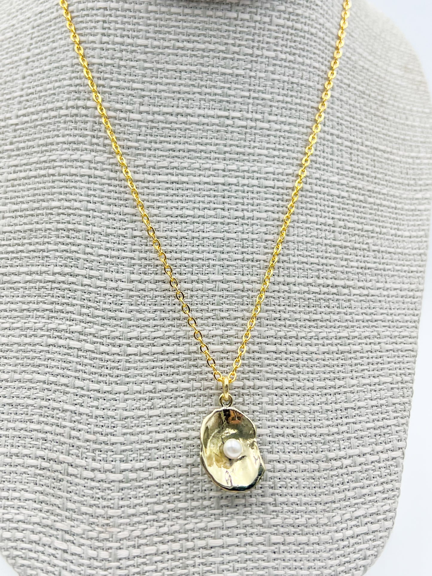 Gold necklace with a pendant on a gray textured background