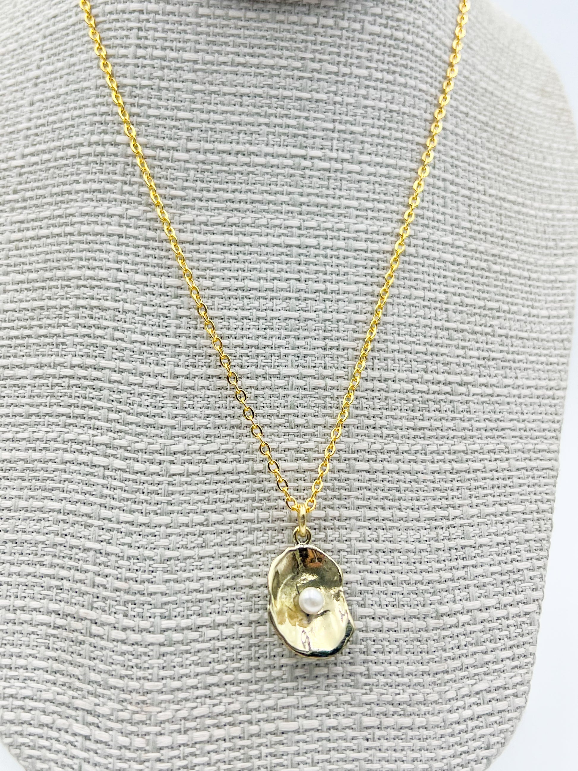 Gold necklace with a pendant on a gray textured background