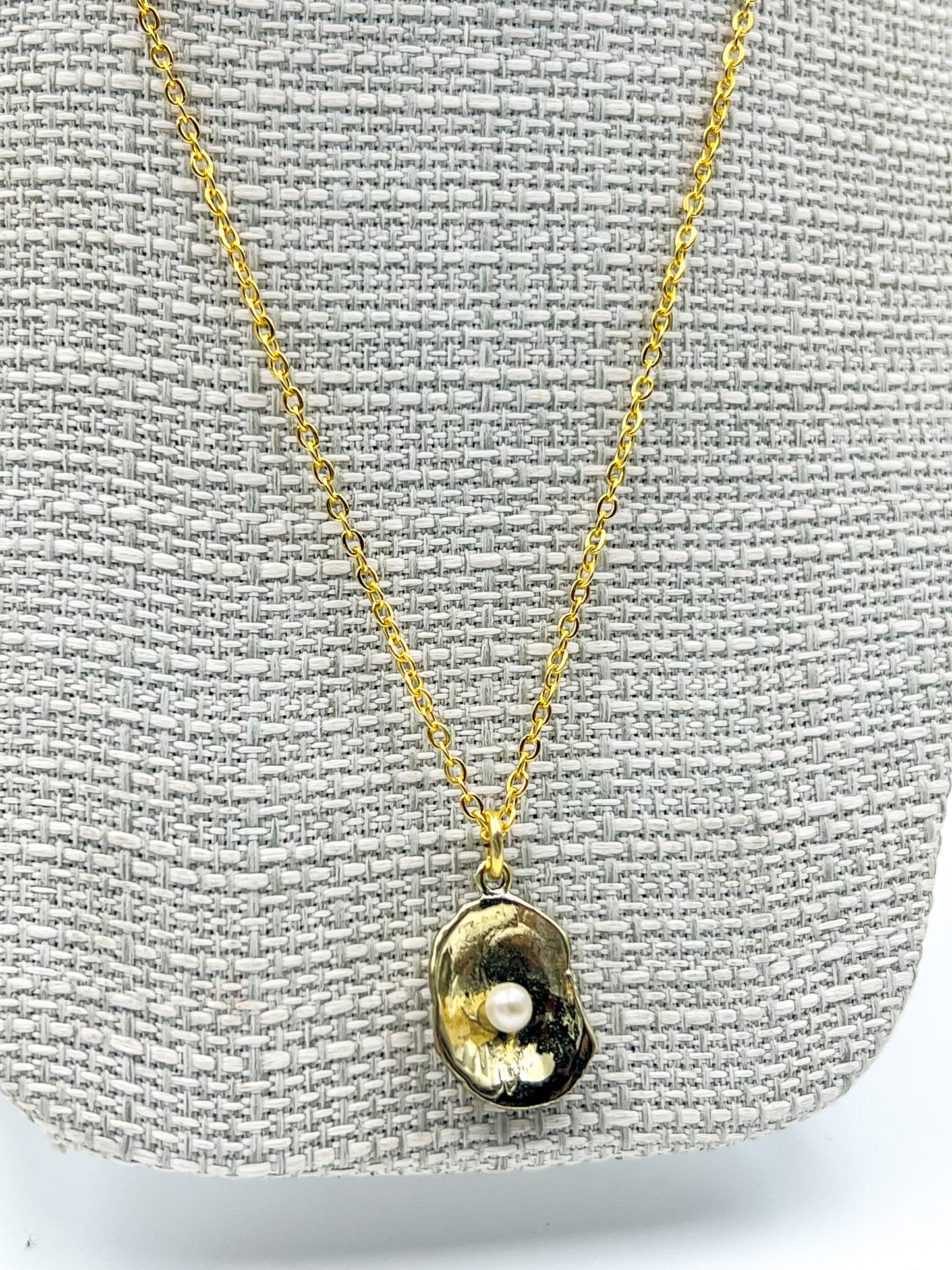 Gold necklace with a pendant on a gray textured background