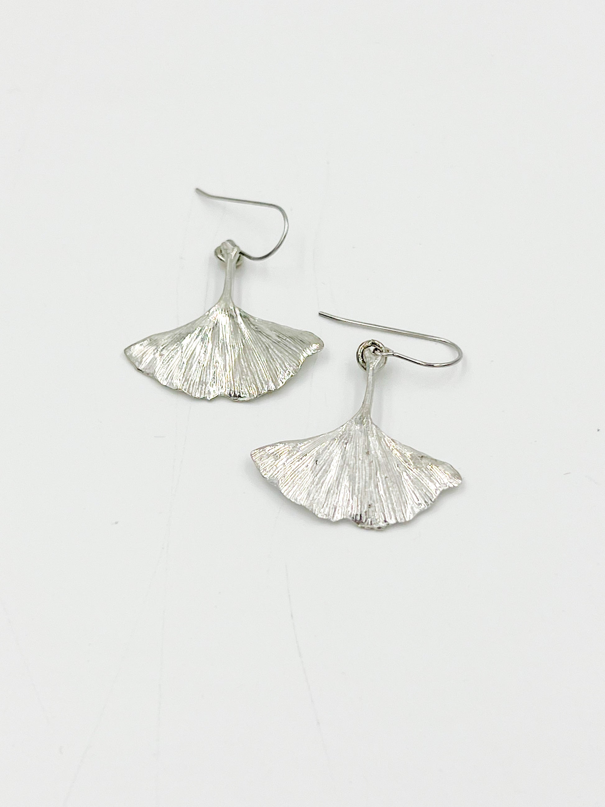 Add some natural charm to your wardrobe with our Ginkgo Wire Earrings! These earrings are crafted from highly polished pewter wire and feature the unique shape of the ginkgo leaf. Made with surgical steel, these earrings measure 1.25 inches for a comfortable fit. Get ready to leave a lasting impression with these one-of-a-kind earrings!
