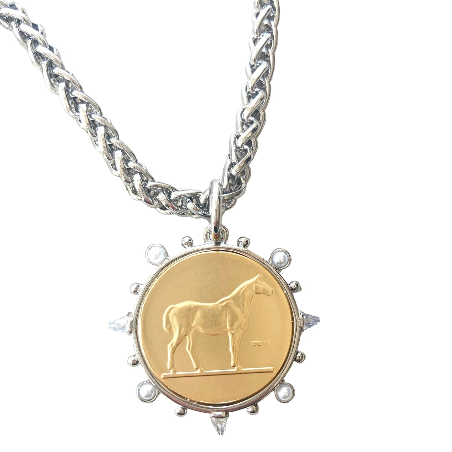 Gold pendant with horse design on a silver chain against a textured white background